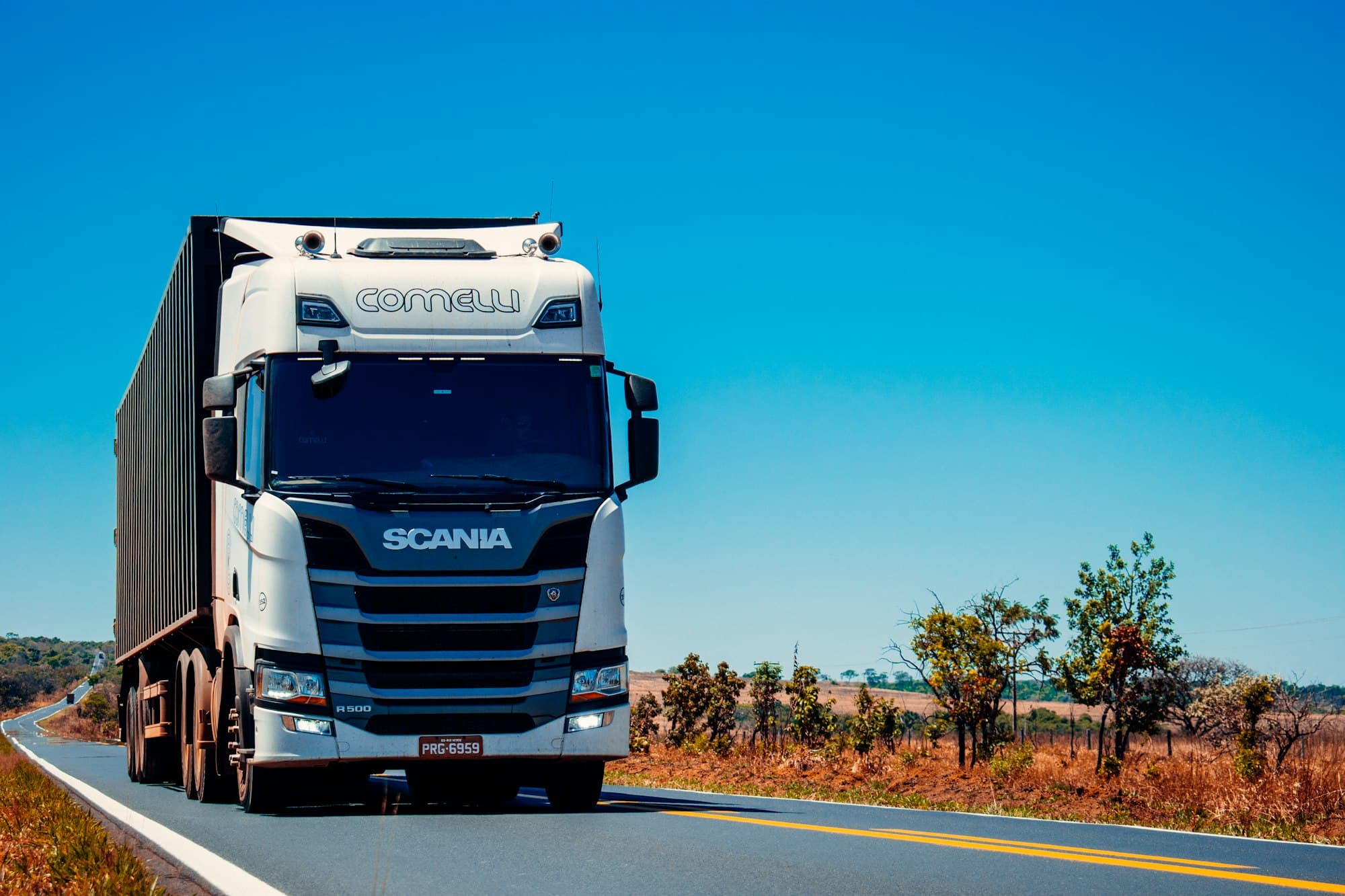 Camion semi-remorque circulant sur une route bordée de végétation